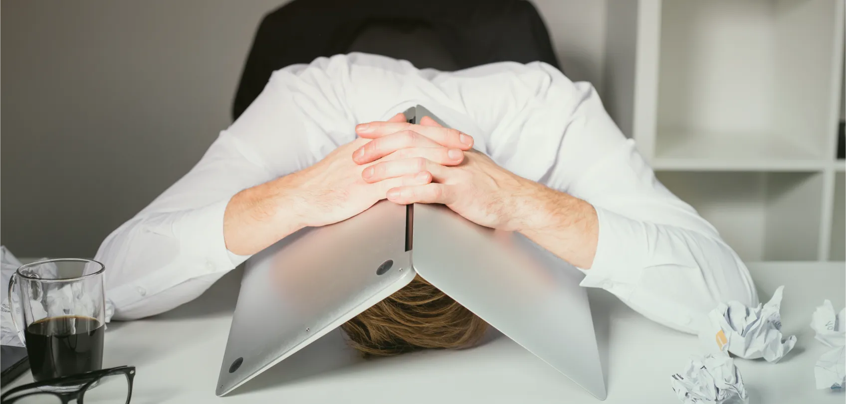 Persona frustrada en su escritorio con una laptop sobre la cabeza, representando los problemas en proyectos web mal gestionados