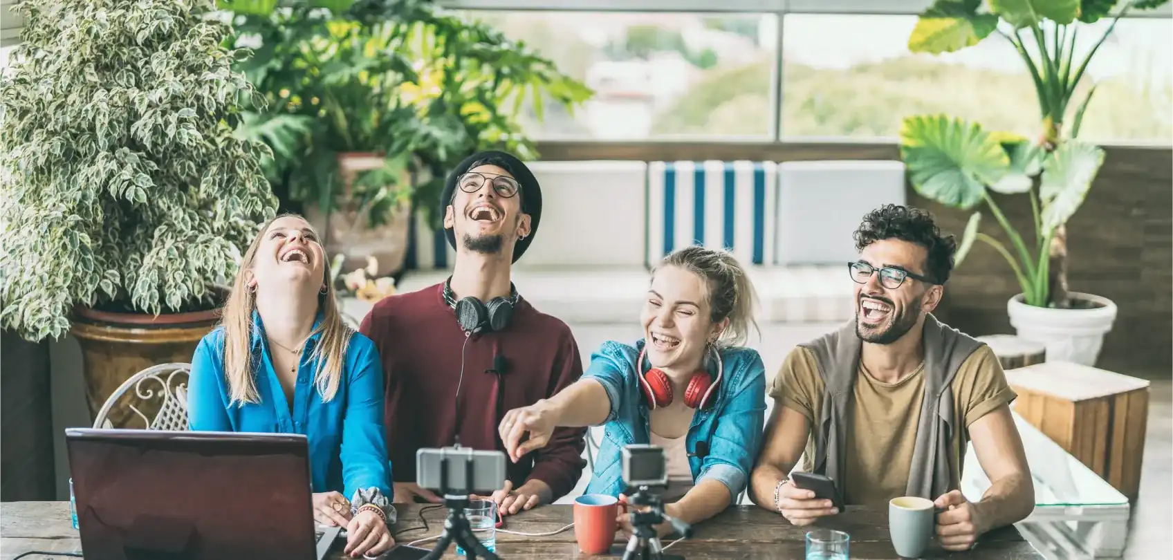 Grupo de jóvenes compartiendo y riendo juntos mientras crean contenido digital en un ambiente relajado y colaborativo.