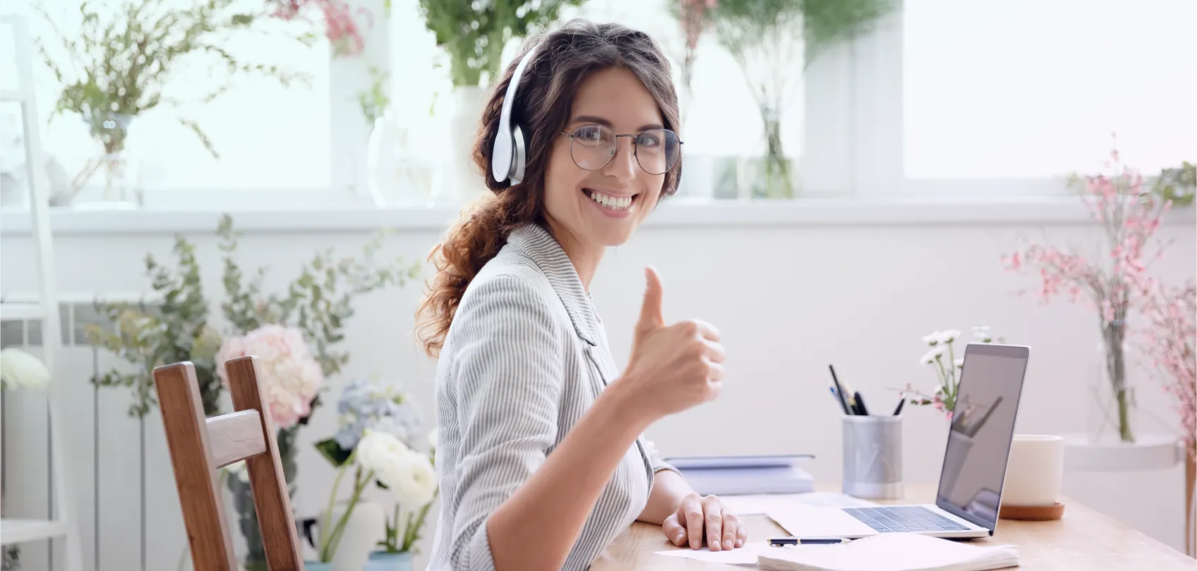 Profesional sonriente con audífonos trabajando en laptop y levantando el pulgar, simbolizando la eficiencia de los CMS Headless frente a los tradicionales