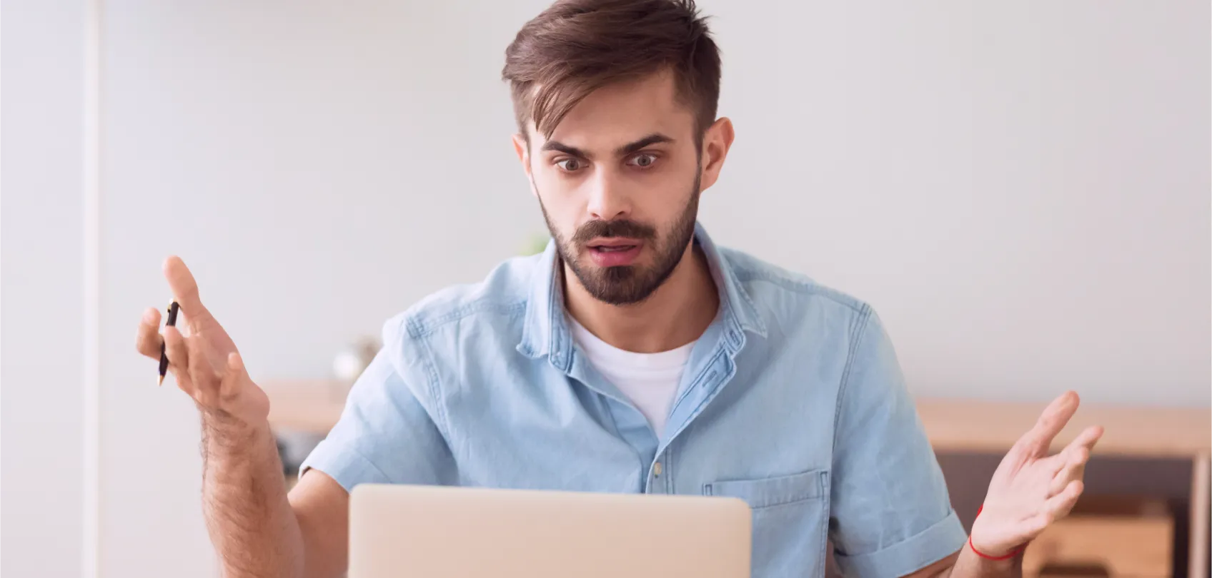 Hombre sorprendido frente a una computadora portátil, representando la frustración al lidiar con trolls en Internet